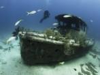 Female scuba diver swimming underwater near a shipwreck in the Bahamas;  