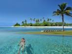 Woman swimming in the infinity pool under the sun in beautiful tropical beach resort in the Bahamas.