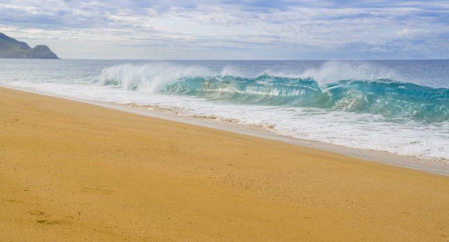 Clear, blue, waves break on the shore of a Pacific coast beach in Todos Santos, Baja California Sur Mexico.