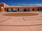 A traditional adobe building located on Museum Hill in Santa Fe, New Mexico. Front plaza area shows unusual paving detail.